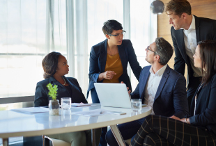 Business group going over  topics while looking at a laptop 