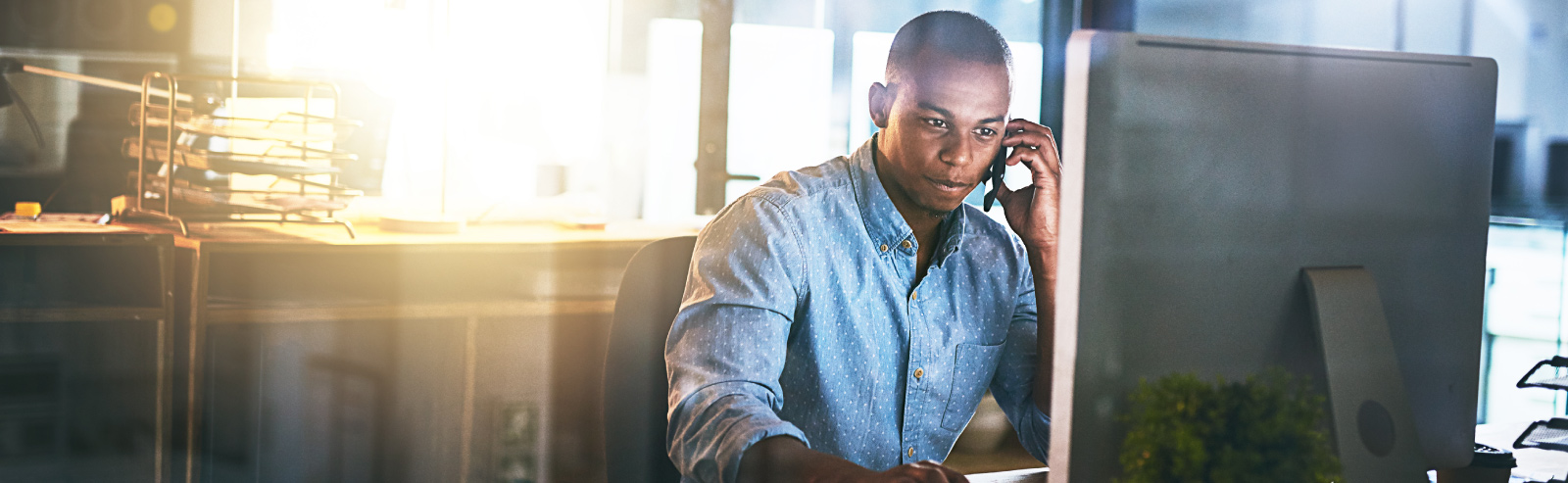 Man talking on the phone looking at a desktop computer